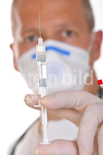 Physician wearing a virus-proof face mask, holding a syringe