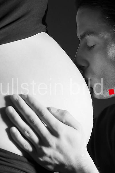 Expectant father is kissing the belly of his pregnant partner