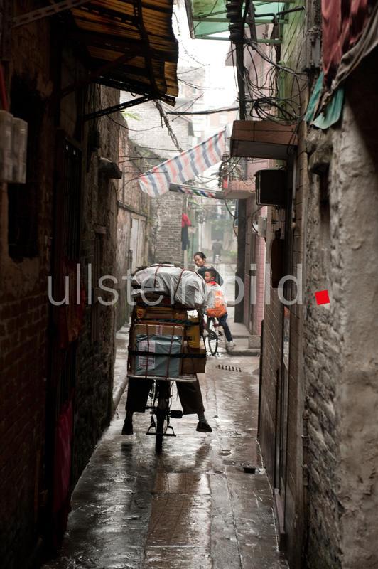 Guangzhou, China, Radfahrer mit voller Ladung in einer schmalen Gasse
