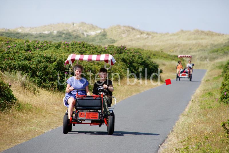 Wangerooge, Deutschland, Urlauber unterwegs mit einem Dinocar